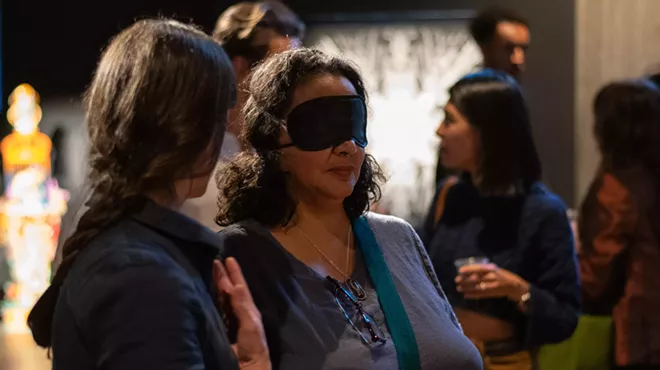 Blindfolded woman explores an art gallery.