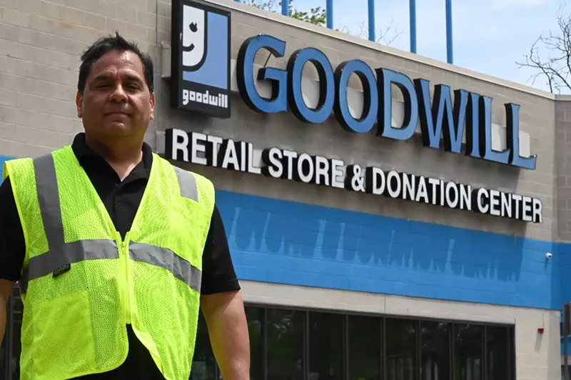 Image: A man stands in front of a store.