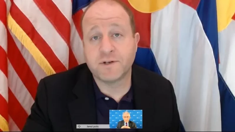 Image: Governor Jared Polis introducing Dr. Anthony Fauci (bottom center of the screen), during a December 1 press conference.