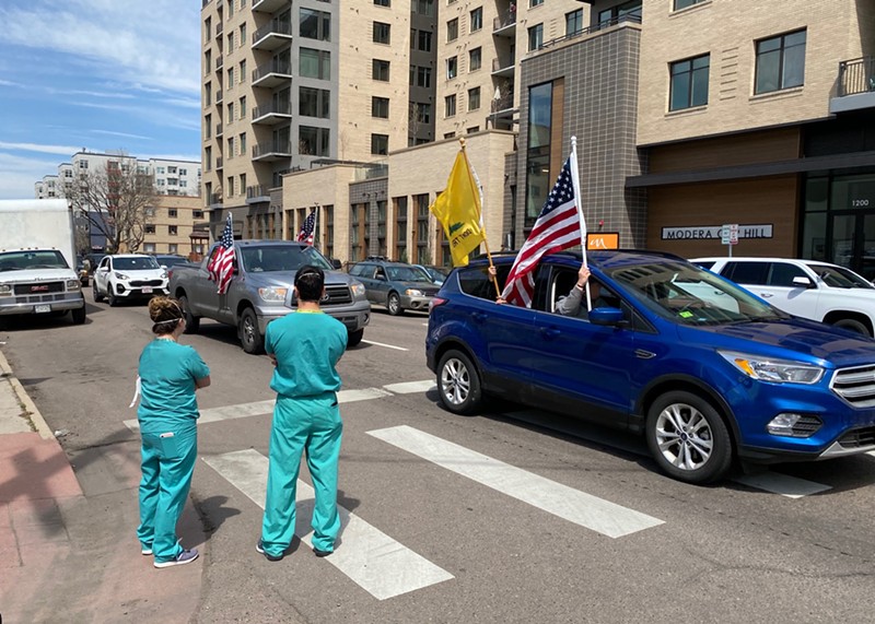 Two Denver health-care workers watch anti-shutdown protesters near the Colorado State Capitol.