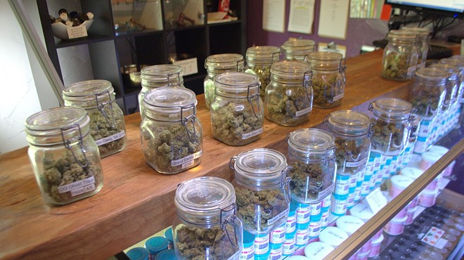 Jars of marijuana flower lined up on a dispensary shelf