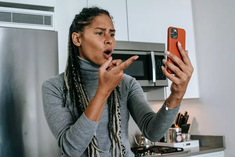 Image: a woman pointing at a phone indignantly