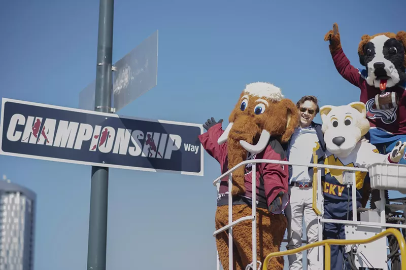 Image: Several mascots and a man stand next to a sign that reads "Championship Way."