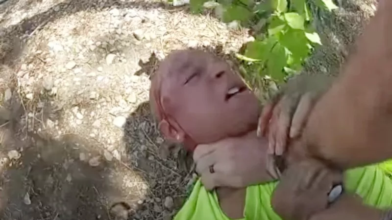 Image: This screen capture from an Aurora Police Department video shows a bloodied Kyle Vinson being choked by Officer John Haubert, who was arrested for his actions during the July 23 incident.