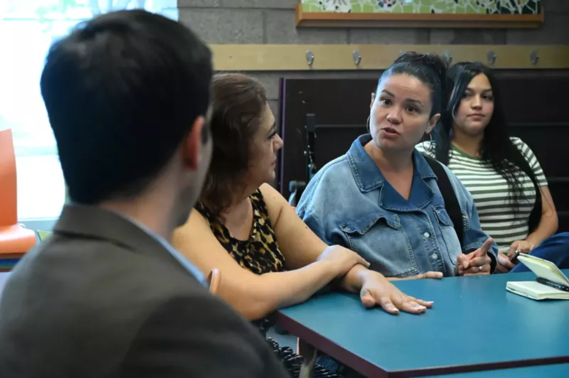 Image: A woman speaks to someone at her table.