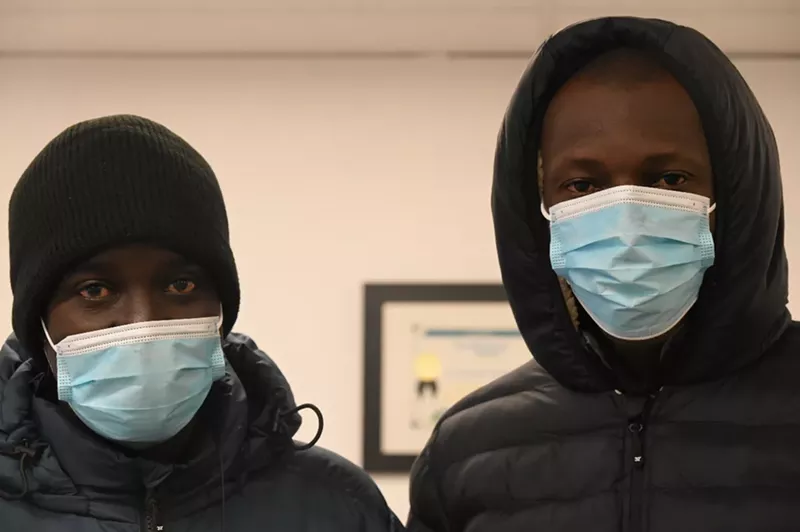 Image: Two Mauritanian migrants stand with masks on.