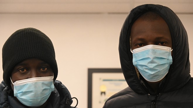 Two Mauritanian migrants stand with masks on.