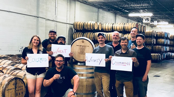a group of people stand around whiskey barrels holding signs