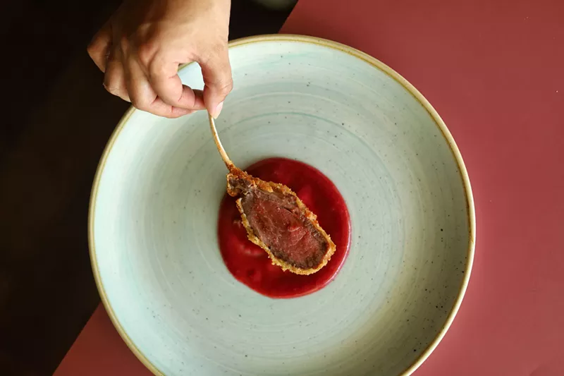 Image: hand holding the end of a bone on a piece of meat