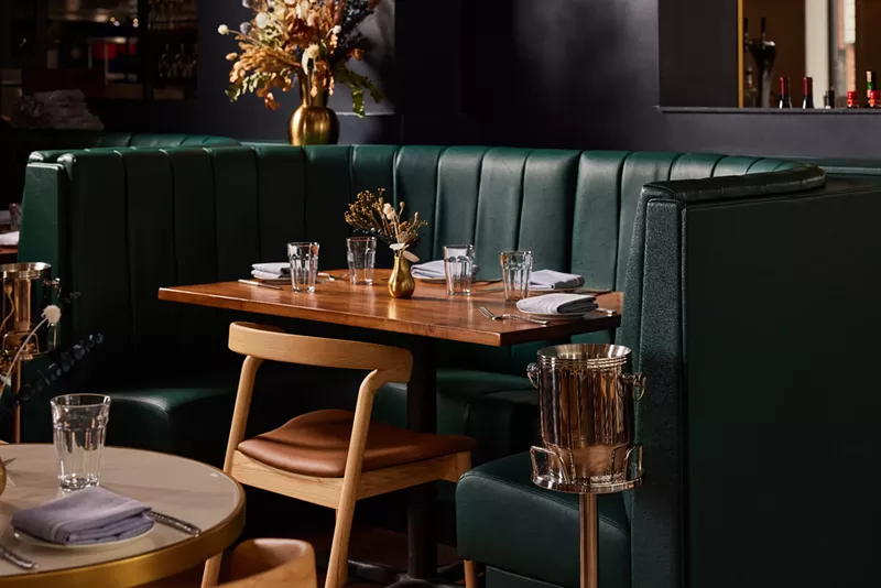 Image: a wooden table in front of a green booth