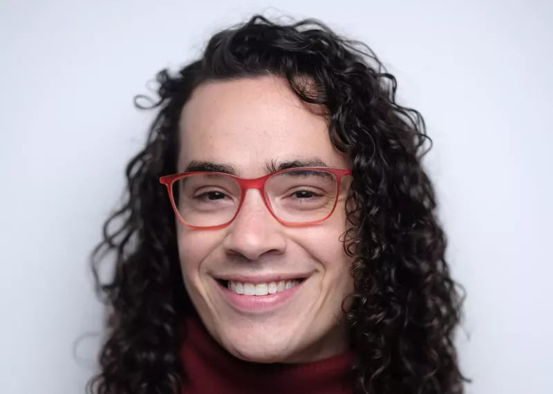 Image: Headshot of a curly haired man in pink glasses.