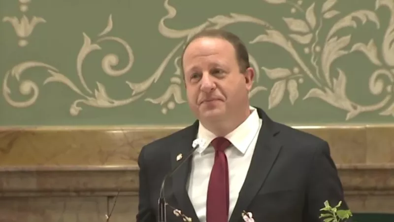 Image: Governor Jared Polis at the podium in the House chamber.