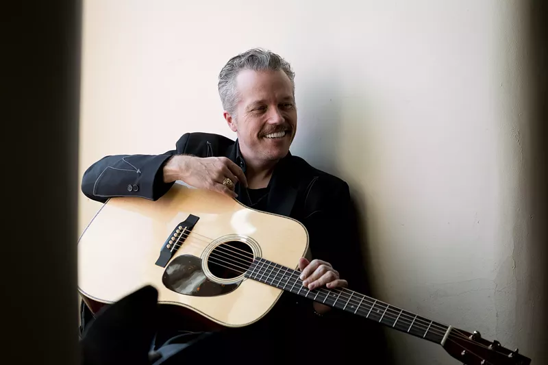 Image: Jason Isbell smiles while holding a guitar