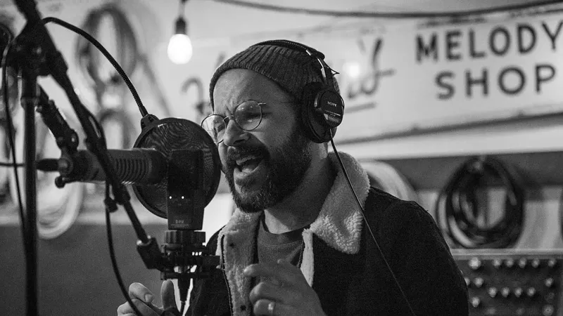 Image: Denver-based musician Jem Zornow sings into a microphone in a recording studio.