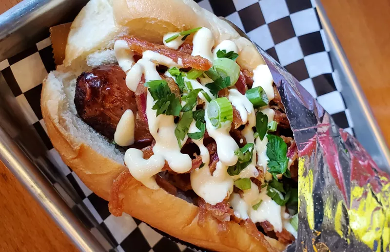 Image: a sausage in a bun with various toppings