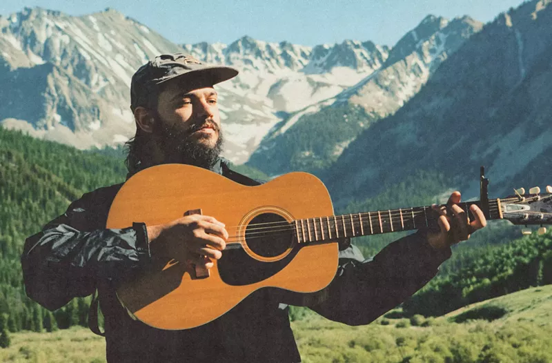 Image: man holding acoustic guitar in the mountains