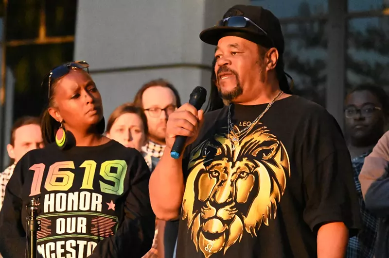 Image: Man with hat speaks on microphone at protest