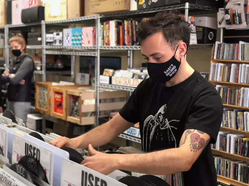 Image: New employee Cole Eckert flips through records at Bart's, soon to be Paradise Found.
