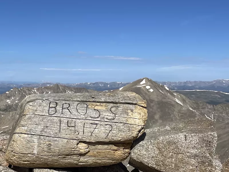 Image: An carved log showing Mt. Bross' elevation and the neighboring Mt. Democrat in the background.