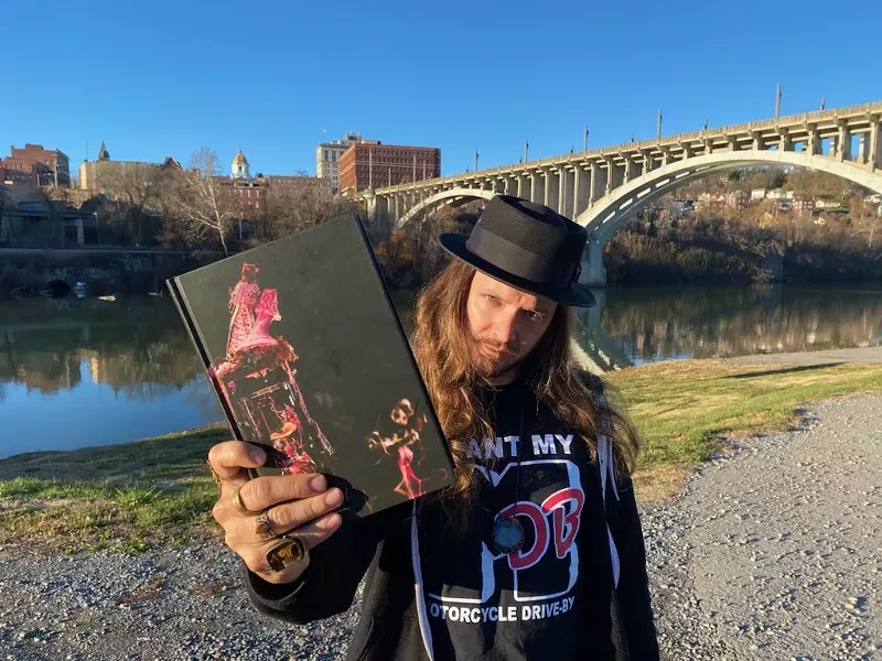Image: man holding a copy of a book outside