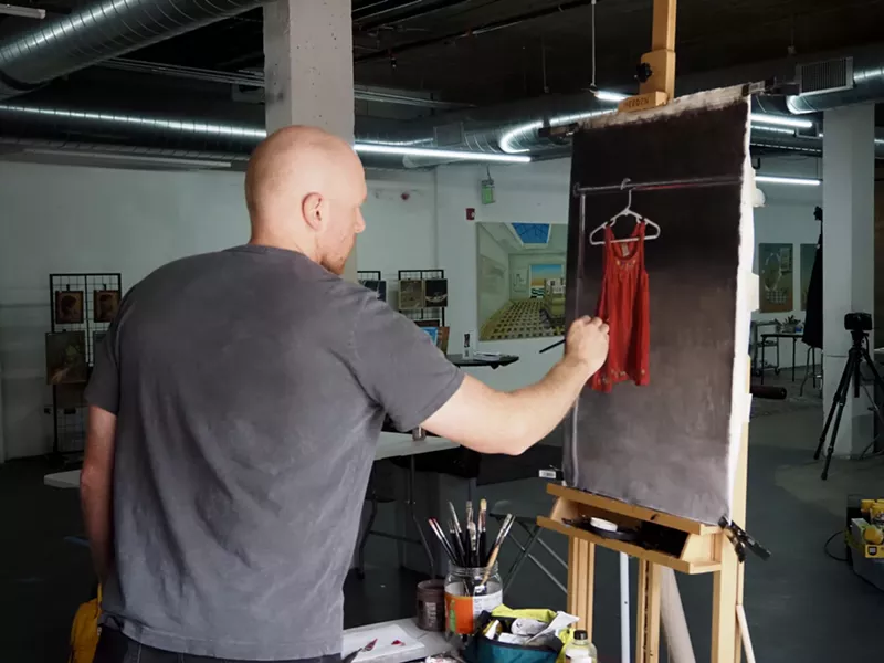 Image: A man works on a painting of an orange dress
