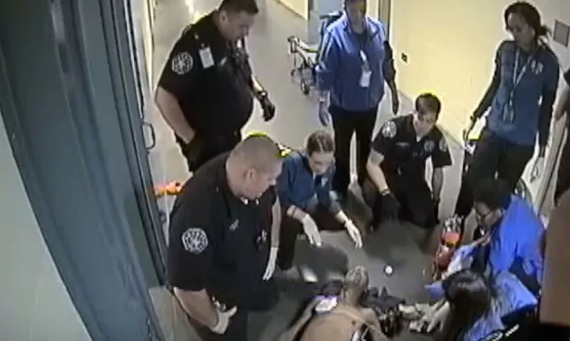 Image: Deputies and emergency personnel looking at the lifeless body of Michael Lee Marshall, as seen in surveillance video. Additional images below.