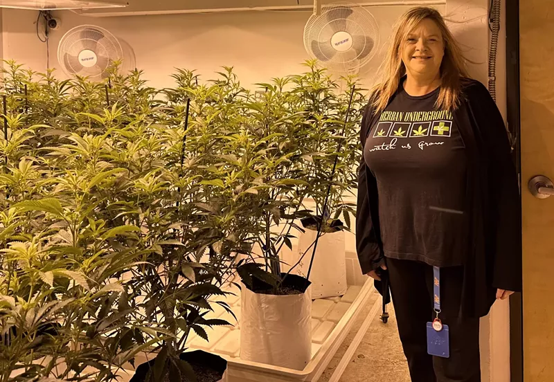 Image: Woman stands in front of indoor marijuana plants