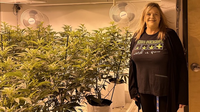 Woman stands in front of indoor marijuana plants