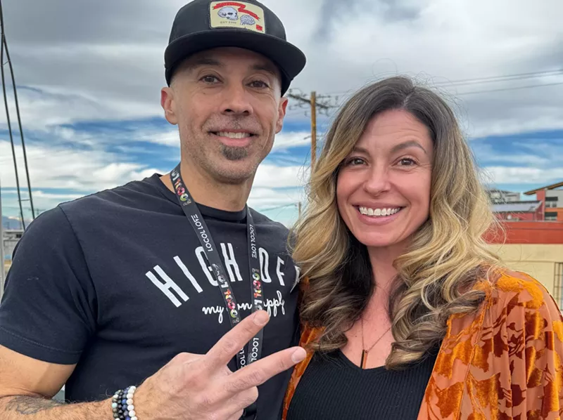 Image: husban and wife pose, man makes a peace sign