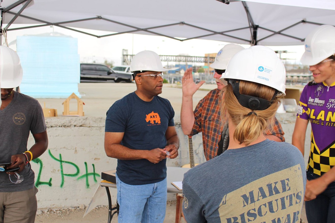 Mayor Hancock dons a hard hat and talks to individuals at a tiny-home village being constructed in RiNo.