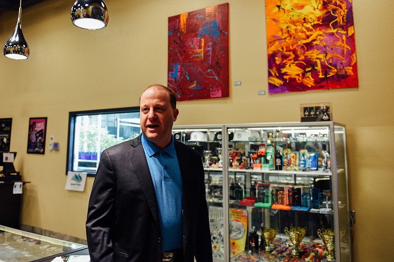 Governor Jared Polis, seen here touring a dispensary while campaigning in 2018, has been sued by a medical marijuana patient.