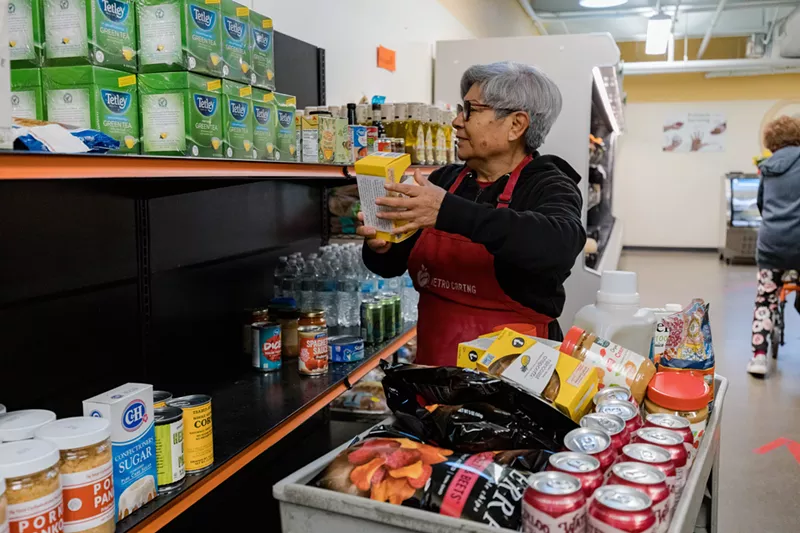 Image: A Metro Caring volunteer stocking shelves at its charitable market