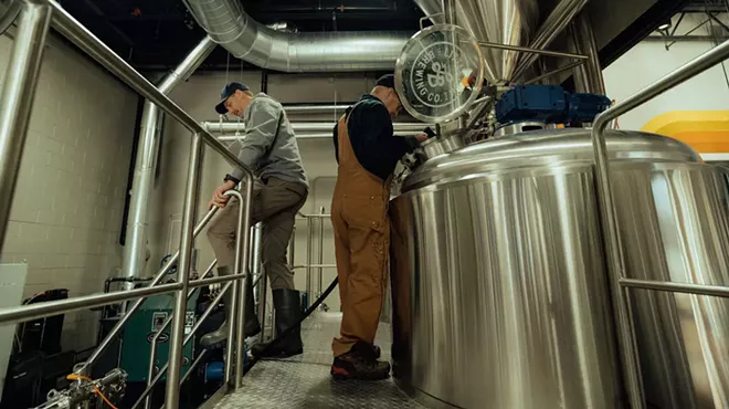 two men near brewing equipment.