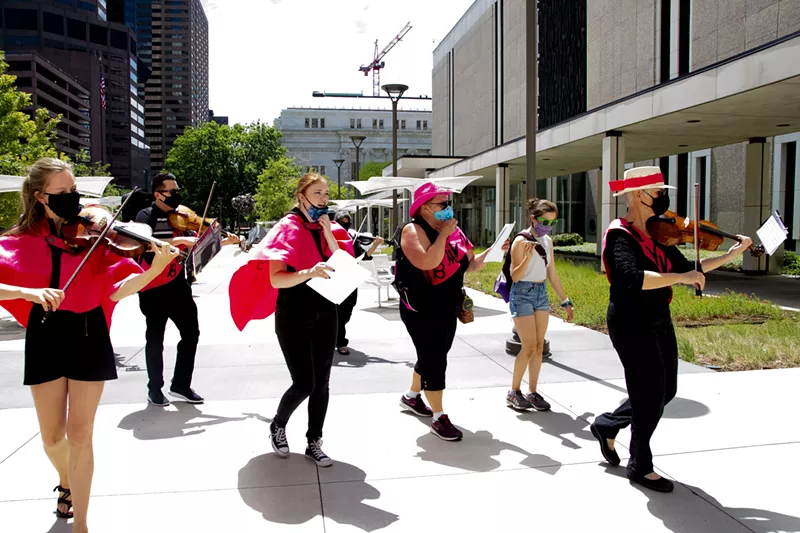 Image: Colorado Symphony violist Helen McDermott leads a procession of musicians and protestors in front of Senator Cory Gardner's office.