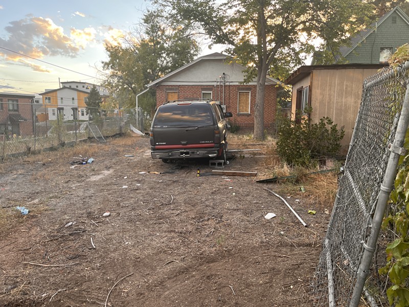 Abandoned cars and trash behind a nuisance property in Denver.