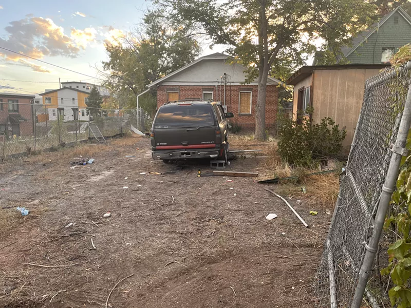 Image: A black SUV sits behind a red-brick home.