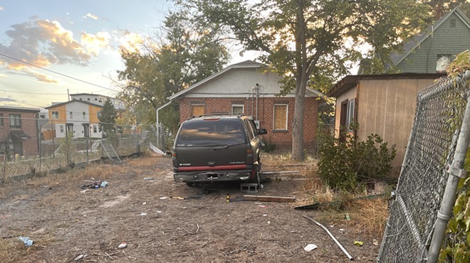 A black SUV sits behind a red-brick home.