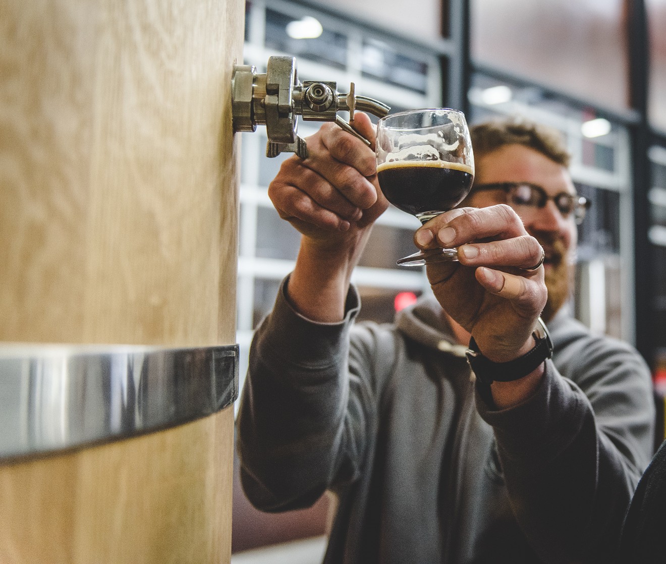 A brewer pours beer from a foeder.