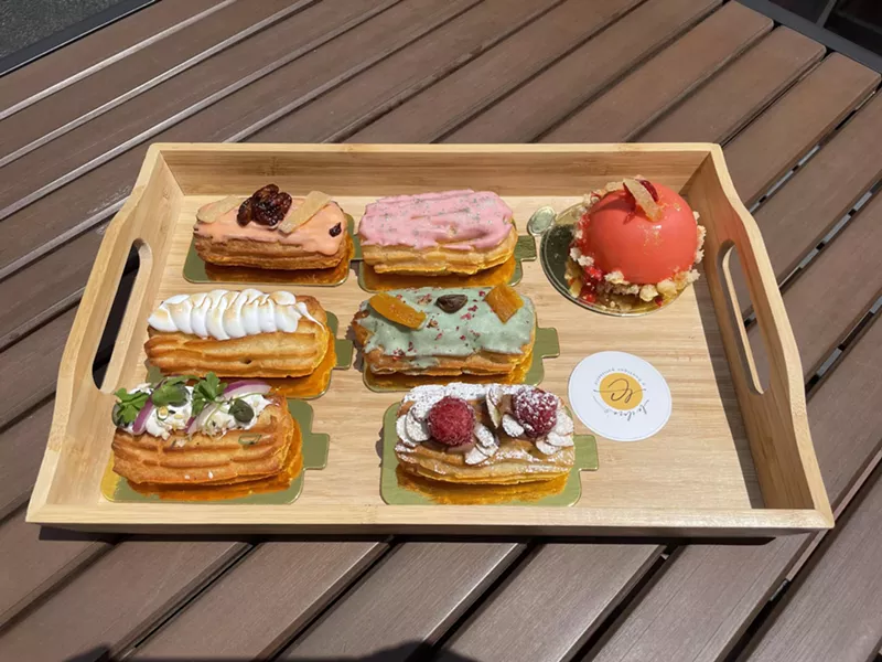 Image: a variety of colorful eclairs on a wooden tray