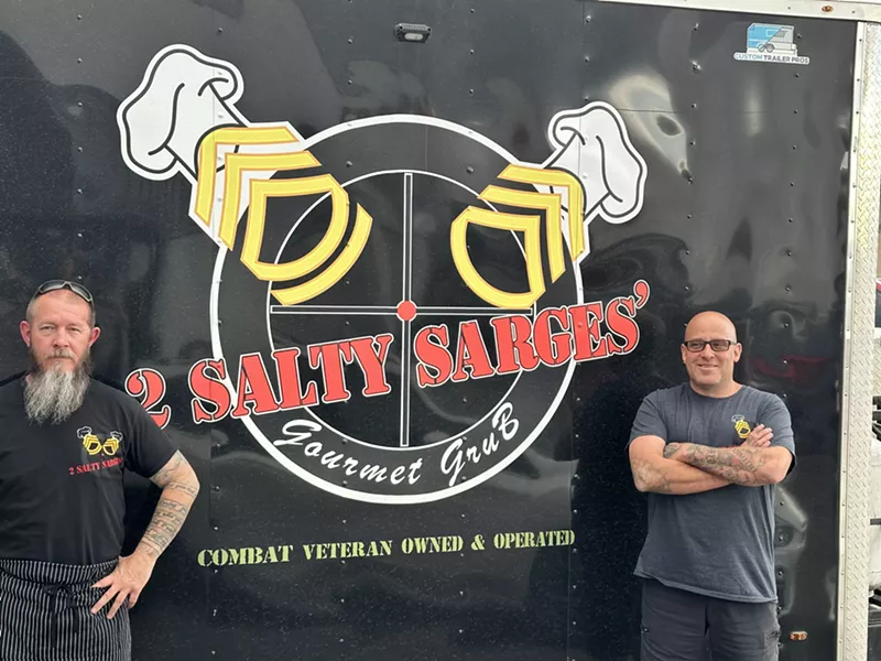 Image: two men standing in front of a black food truck