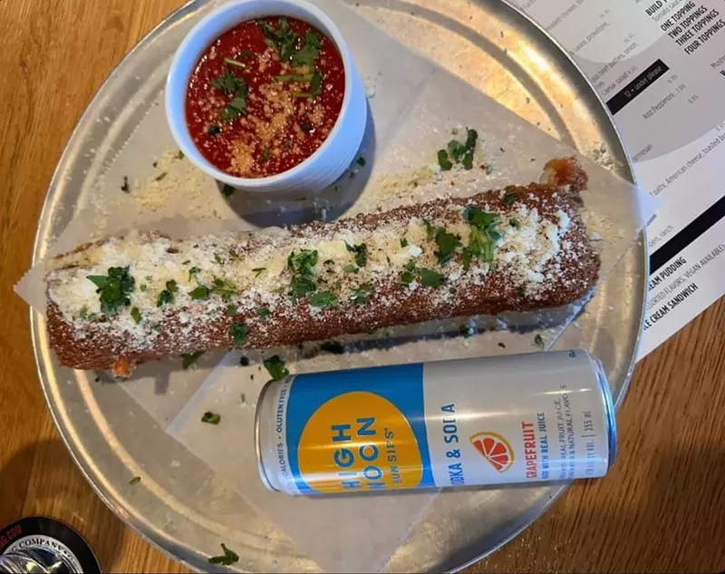 Image: a giant mozzarella stick next to a can of high noon