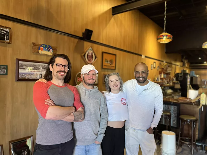 Image: four people standing inside a bar