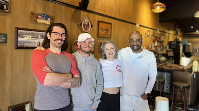four people standing inside a bar