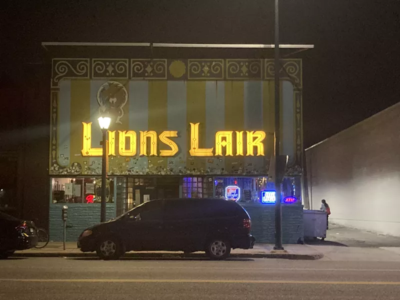 Image: a denver bar with a glowing yellow sign that reads lion's lair