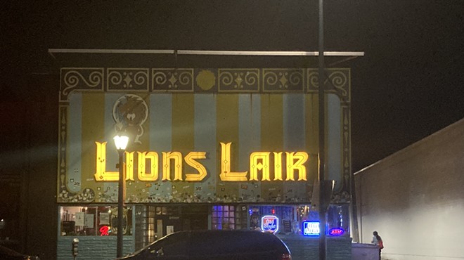 a denver bar with a glowing yellow sign that reads lion's lair