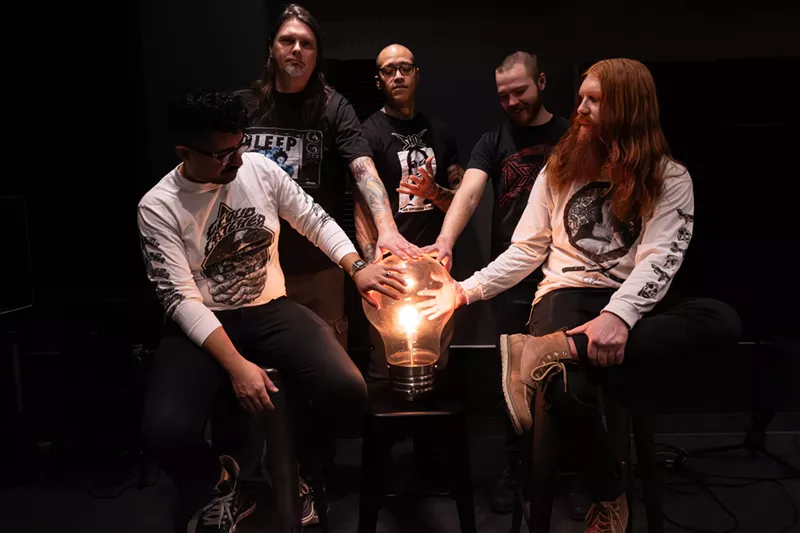 Image: bandmembers gathered around a giant lightbulb