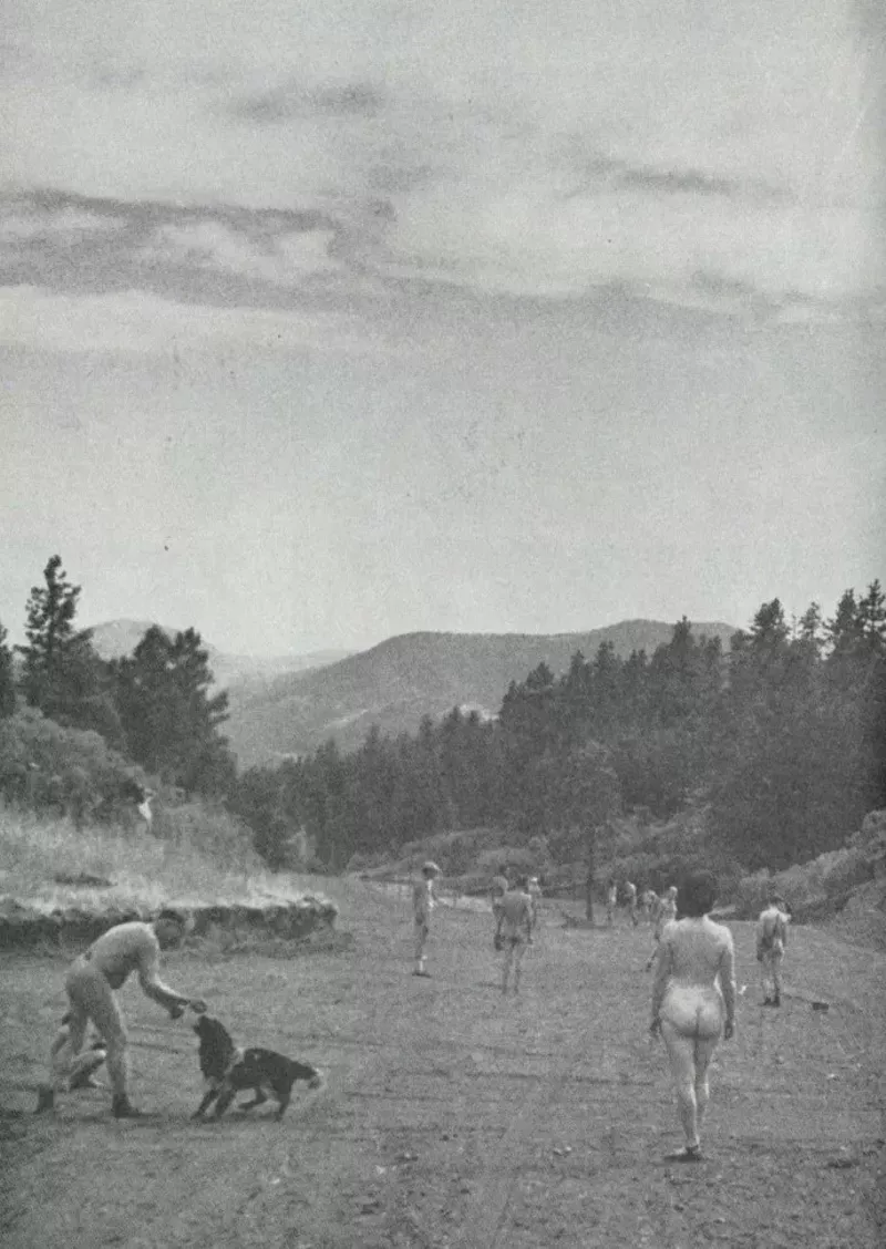 Image: a black and white photo of naked people playing with a dog