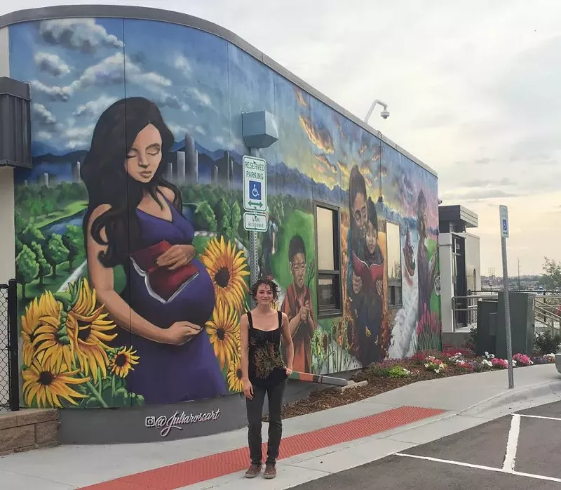 Image: Painter Julia Rose Morgan (@juliaroseart) poses in front of her mural.