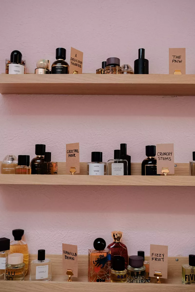 Image: A pink wall with shelves of perfume bottles
