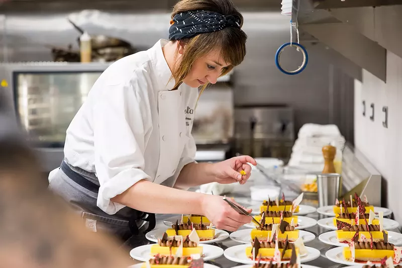 Image: Chef Nadine Donovan plates passion fruit tarts at a charity event.